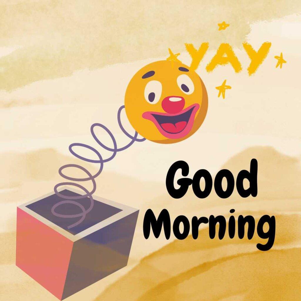 A jack-in-the-box toy with a smiling clown face popping out on a spring, featuring Good Morning text on a sandy yellow background