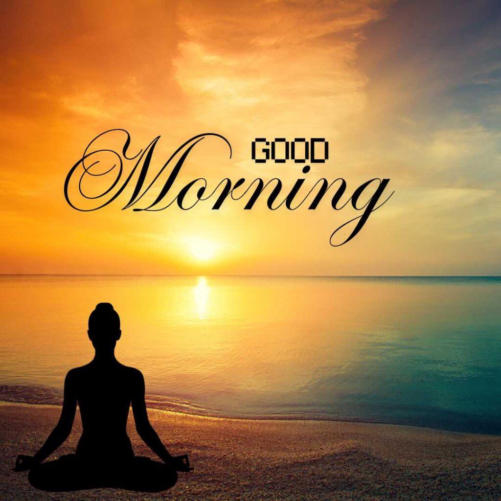 A black silhouette of a person meditating in lotus pose on a sandy beach during a golden ocean sunrise with Good Morning text.