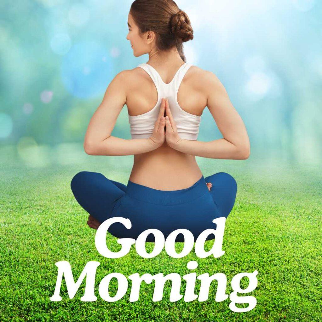 Back view of a woman practicing a reverse prayer yoga pose while sitting cross-legged on a green lawn with a bright bokeh background and Good Morning text.